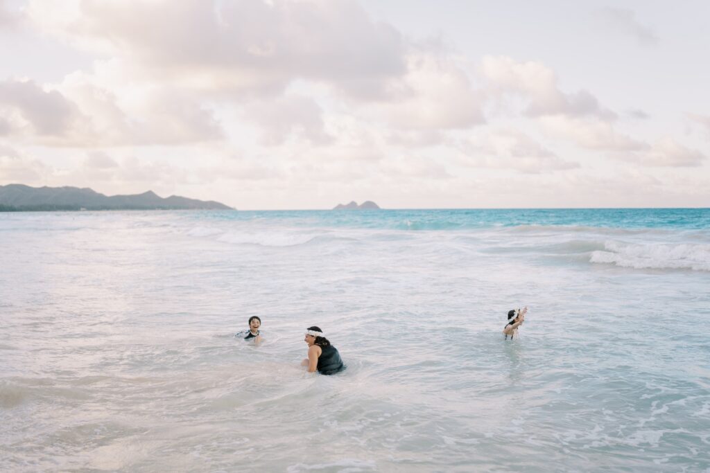 Family playing in the water at the end of a beach photoshoot in Hawaii